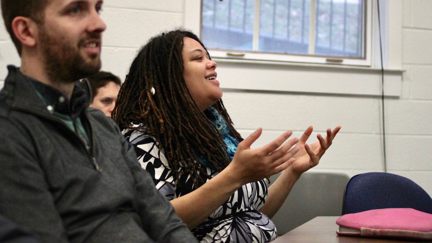 PhD student Alayo Tripp, seated, gesturing forward with her hands, contributing to a conversation