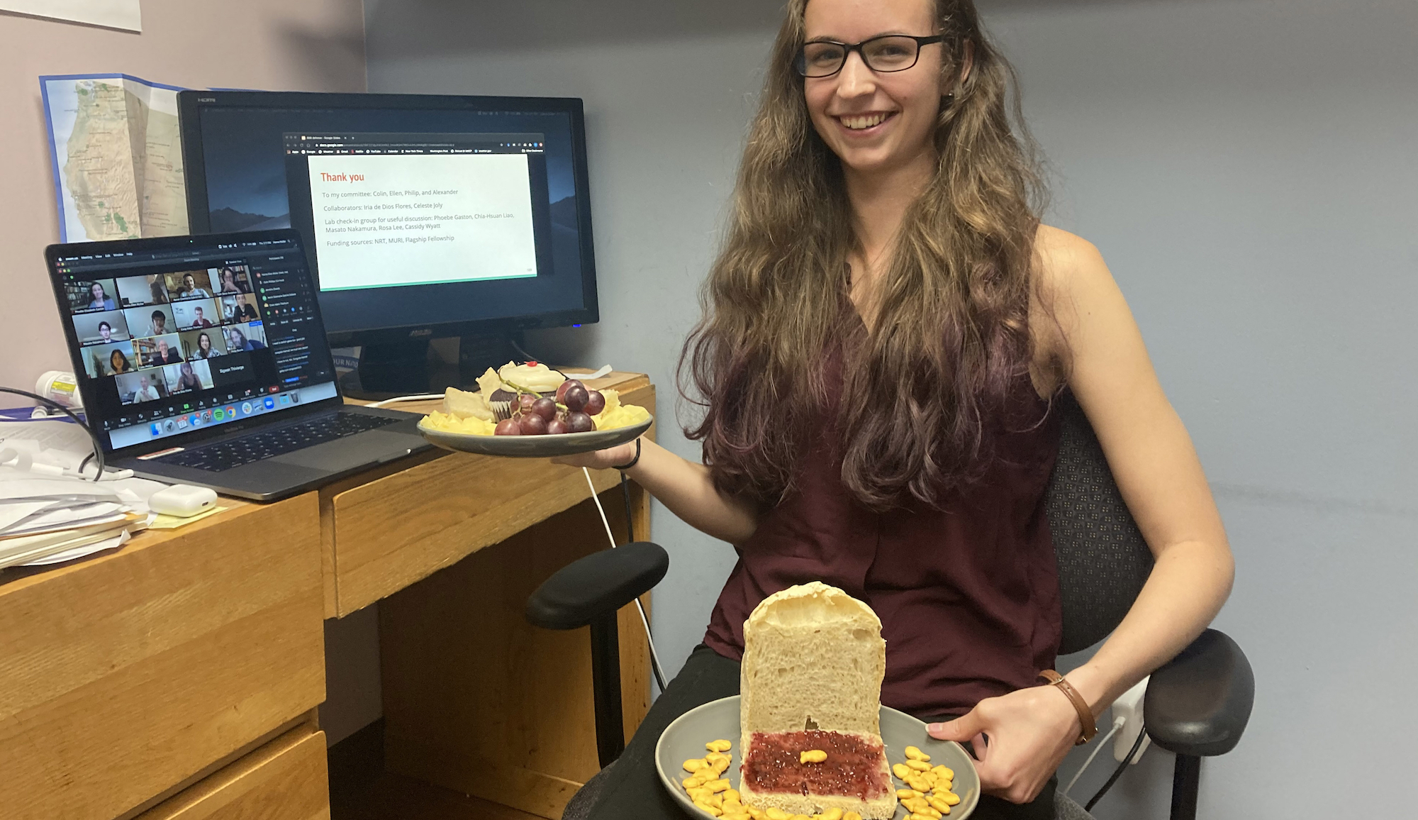 PhD student Hanna Muller, sitting at her office desk after a successful online defense of her 888 research, with a celebratory loaf of bread decorated with Goldfish crackers and raspberry jam, presented as gift by her classmates, one of whom reads aloud this preposterous and ungrammatical sentence: "A goldfish that no 888 defendant would turn down has ever had problems appearing in positive jam contexts"