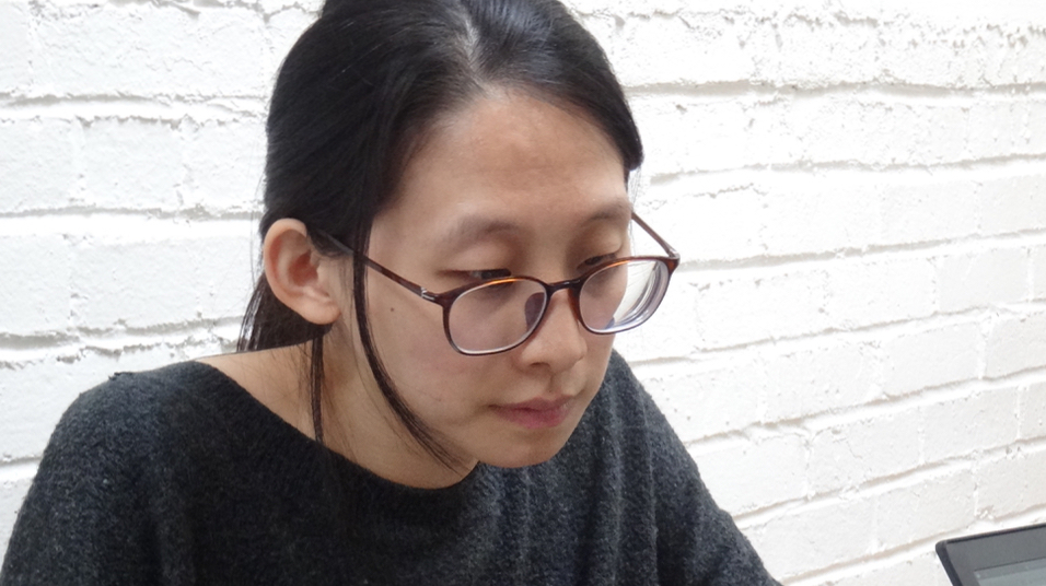 Yu'an Yang, a PhD student in linguistics, concentrating on her laptop screen