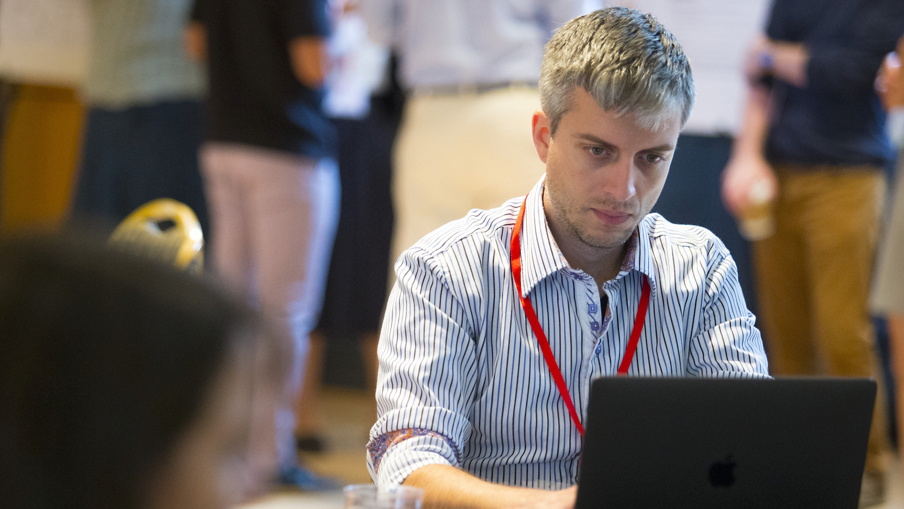 Postdoctoral fellow Dan Goodhue, sitting at a table in three-quarter profile, looking with concentration at his laptop screen