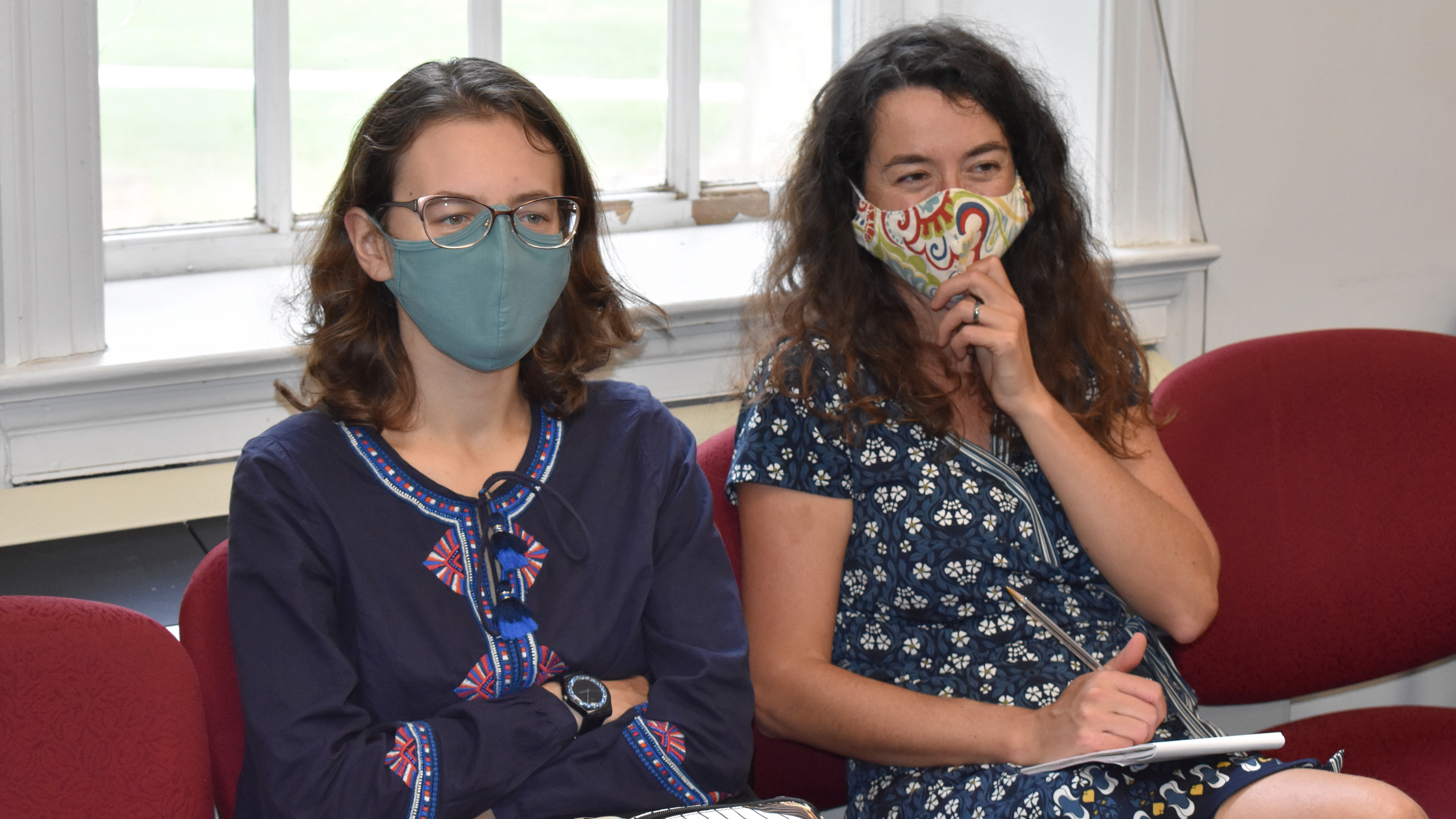 PhD student Polina Pleshak sitting next to Professor Ellen Lau, both wearing covid facemasks and looking straight ahead, but smiling
