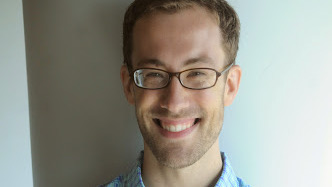Close portrait of a man with a thin face, blonde hair, glasses, and a stubbly chin, smiling delightedly at the camera: Lo, it be Stefan Keine, Assistant Professor of Linguistics at UCLA.