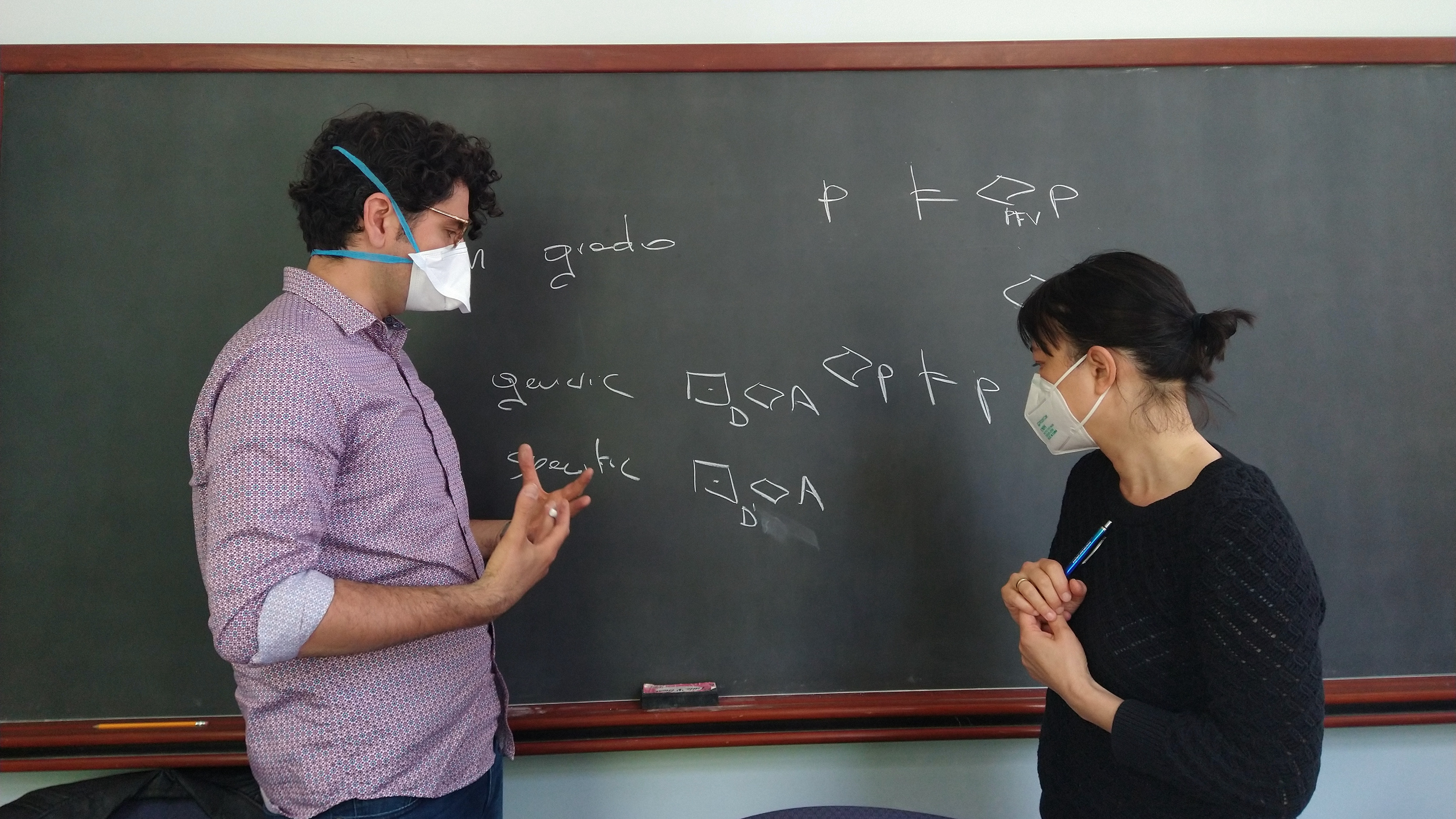 A chalkboard covered in logical notation, with a man and a woman standing in front of it, arguing.