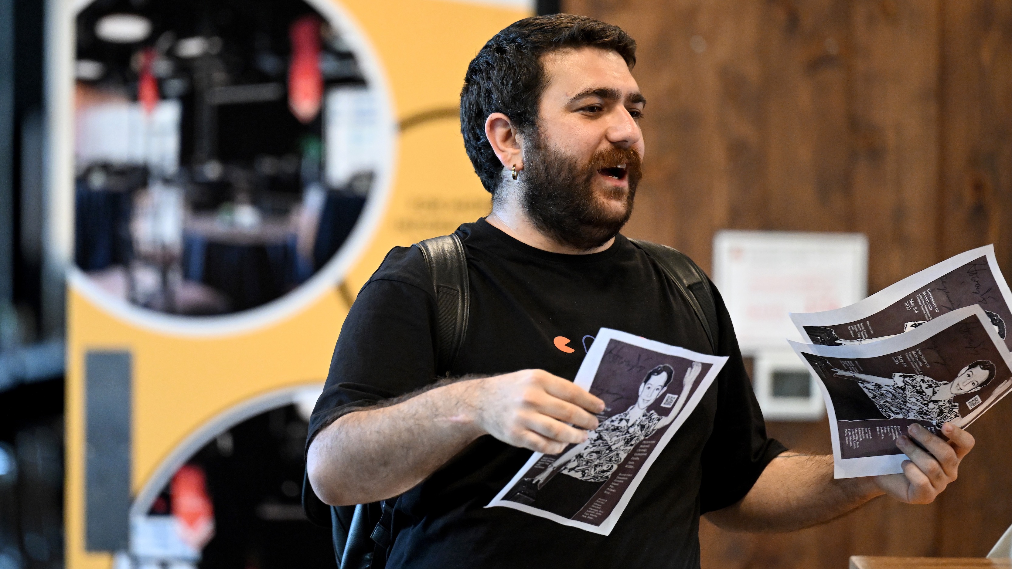 A young man with a beard, distributing flyers.