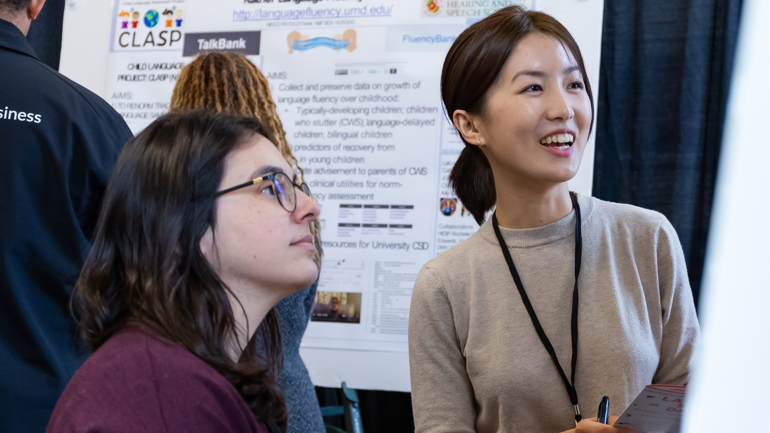 Two young women standing at a poster presentation of research.