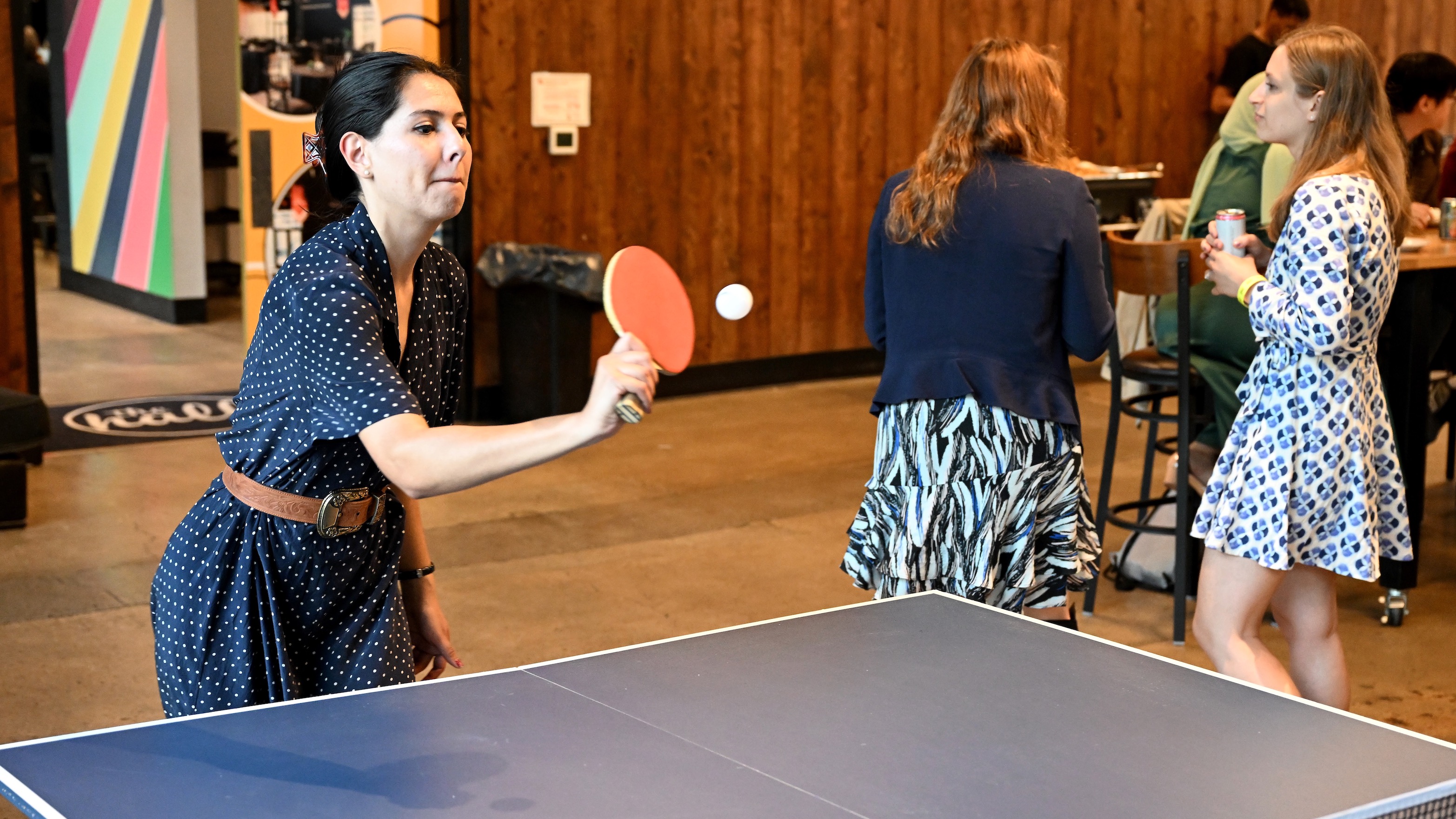 A young woman playing table tennis casually, concentrating on hitting the ball with her paddle.