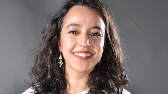 Close studio portrait of a young woman, smiling.