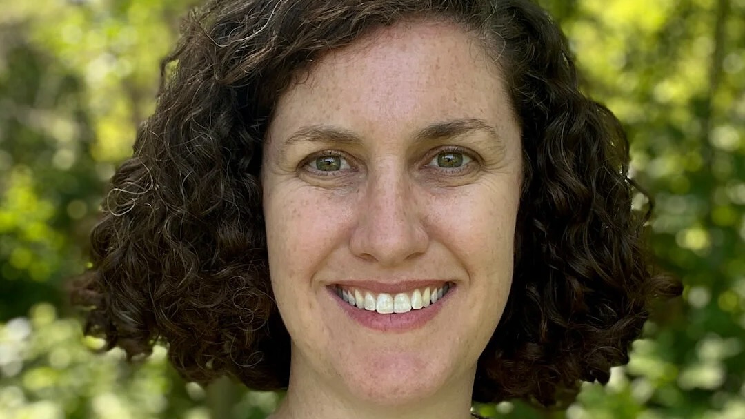 Close photo of a smiling woman, outside.