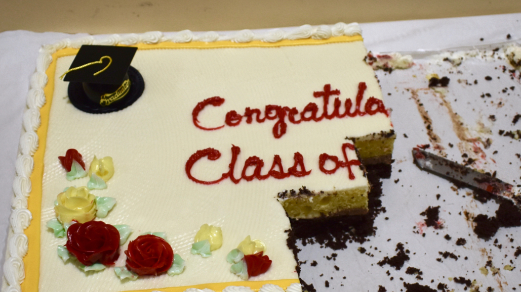 Close photo of a half-eaten sheet cake; still readable on top are the words "Congratulations Class of...," but this trails off into crumbs. 