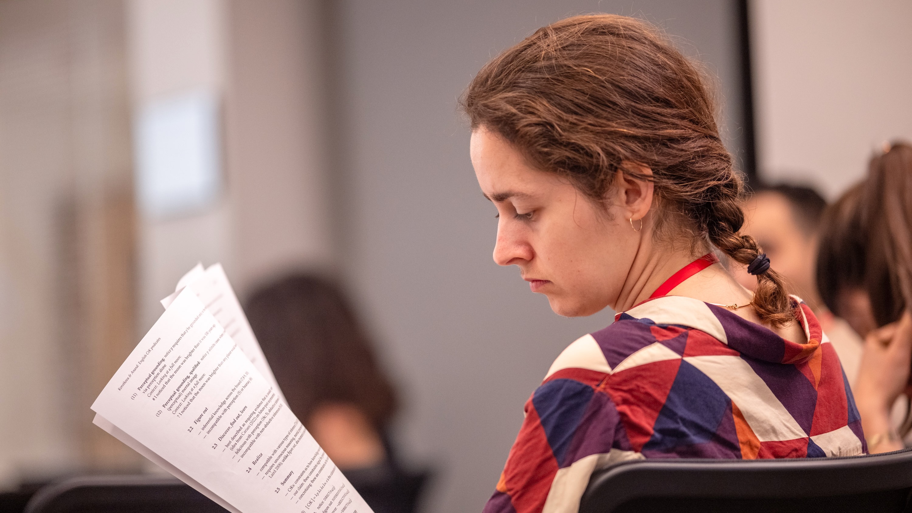 A young woman reading a sheet of paper.