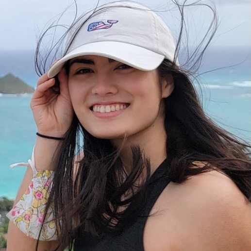A young woman in a wide cap, with tropical waters in the background.